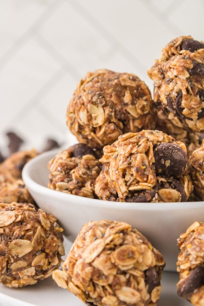 Classic energy bites with chocolate chips and oats, in a white bowl and some out of bowl.