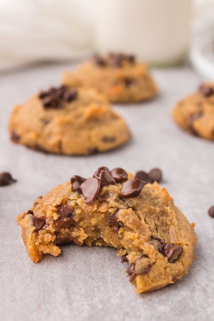 Chocolate Chip Chickpea Cookies with a bite taken out of it, still on parchment paper.