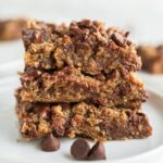 3 vegan peanut butter blondies stacked on top of each other on a white plate.
