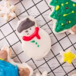 Vegan Sugar Cookie on a black cooling rack. A decorated snowman cookie is in the center.