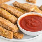 Tofu sticks on a white plate with marinara sauce.