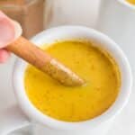 Turmeric latte in a white mug and with a cinnamon stick.