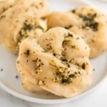 3 vegan garlic knots on a white plate.