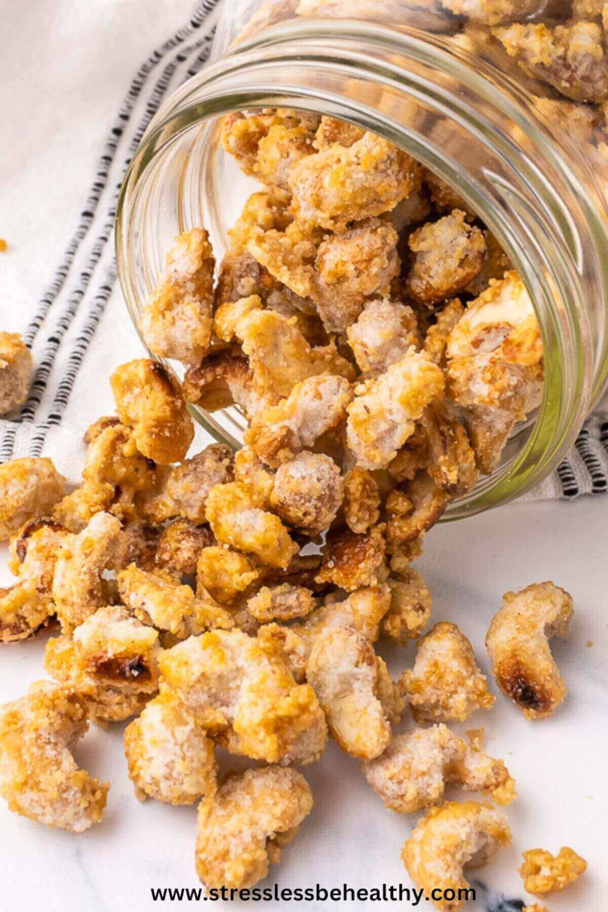 Candied cashews spilling out of wide mouth mason jar.