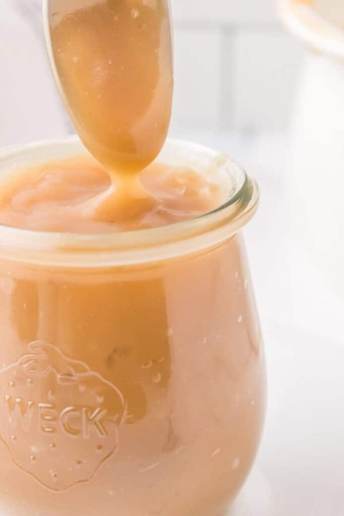 Close of of caramel sauce being drizzled over a glass weck jar.