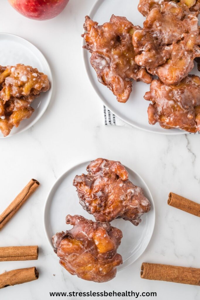 Vegan apple fritters on multiple plates in an overhead view of the counter top.