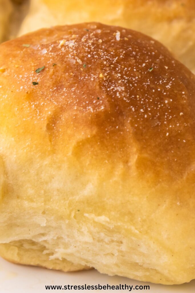 Close up image of homemade vegan dinner rolls, so you can see the fluffy and soft insides and golden tops.