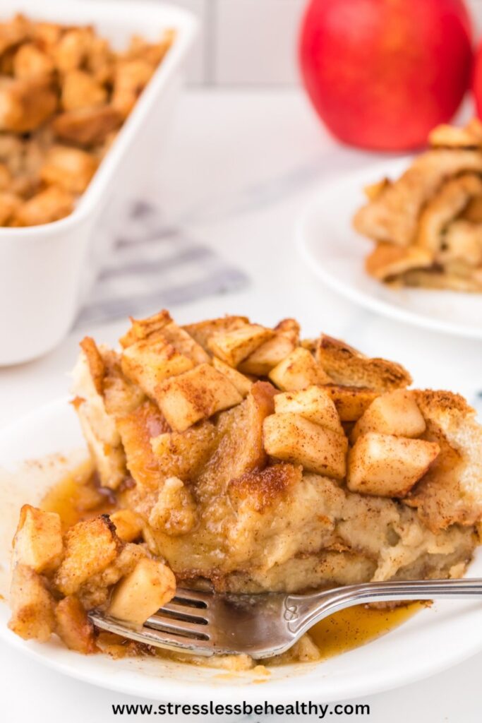 A single piece of apple french toast casserole that's dairy free, with a bite missing and fork on the white plate with the vegan brunch food.