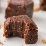 One cashew date bar with a bite take out of it.