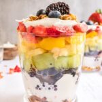 Rainbow parfait in a glass, using 6 different fruits, yogurt, and granola.