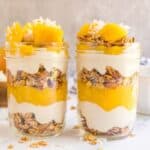 2 mango parfaits next to each other in 8 ounce mason jars.