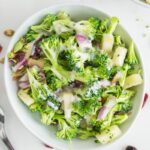 Broccoli salad i na bowl with yogurt dressing on top.