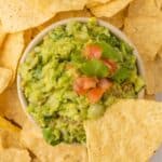 Guacamole in a dish with tortilla chips surrounding it.
