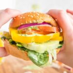 Hands holding a veggie sandwich.