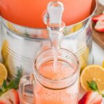 Strawberry lemonade being dispensed from large drink dispenser.