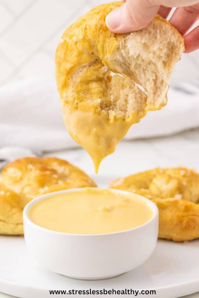 Vegan Soft Pretzel being dipped in vegan cheeze sauce.