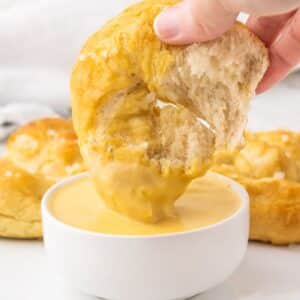 Vegan Soft Pretzel being dipped in vegan cheeze sauce.