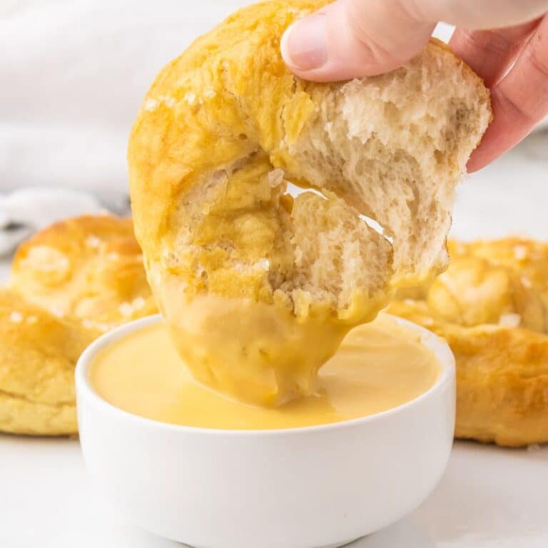 Vegan Soft Pretzel being dipped in vegan cheeze sauce.