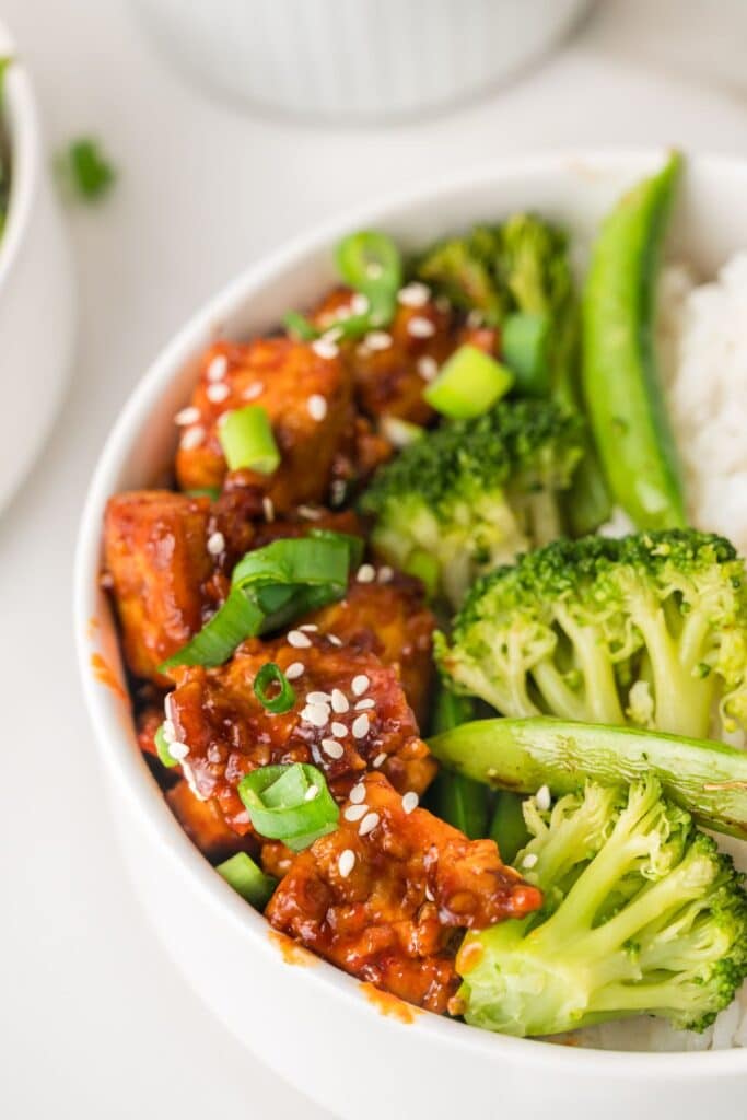 Gochujang tofu in bowl with broccoli, sweet peas, and white rice.